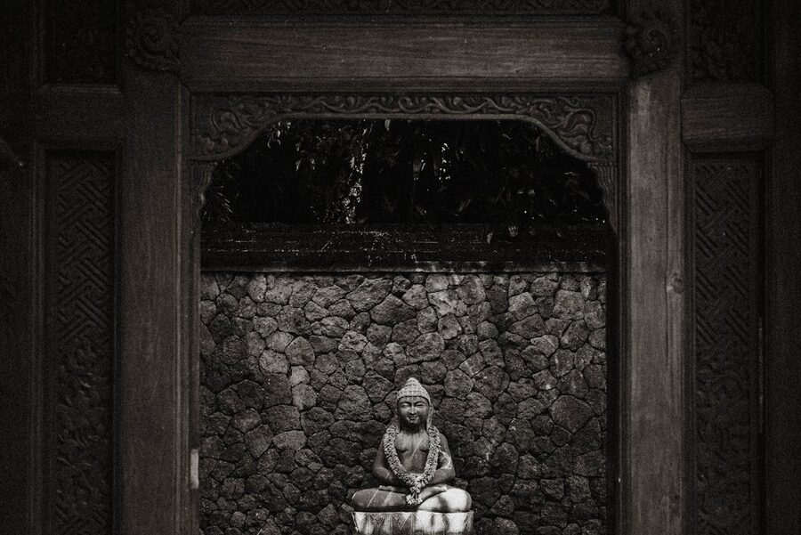 Stone Buddha shrine framed by carved Balinese woodwork
