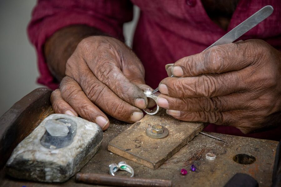 Silversmith shaping a silver ring at a workshop bench