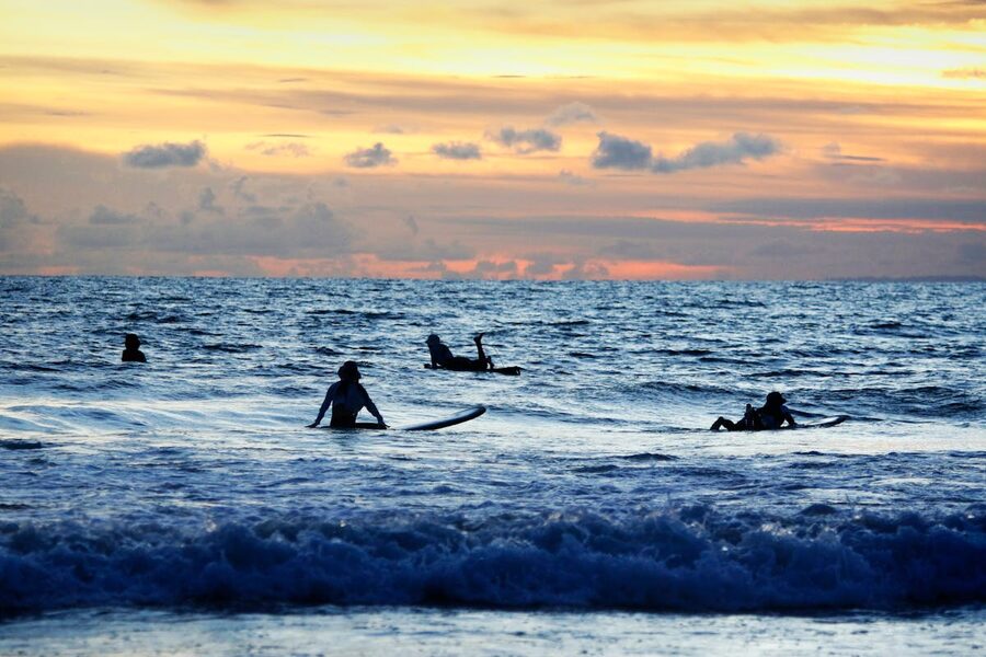 Surfers riding sunset waves on Kuta Beach Bali