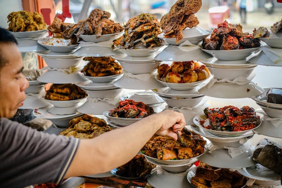 Indonesian food stall display with multiple cooked dishes sitting in white bowls