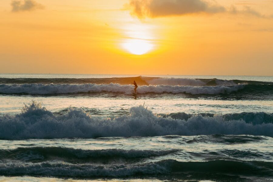 Surfer on a Bukit reef at sunset