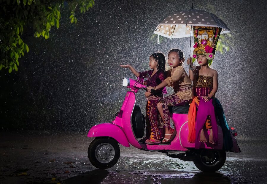 Rainy day in Bali kids on scooter