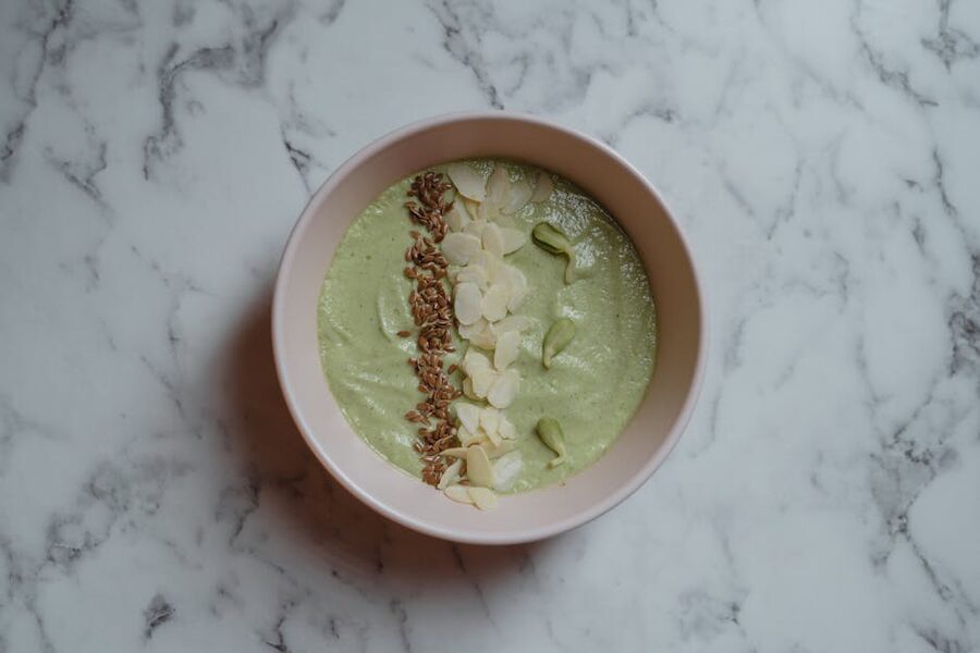 Healthy green smoothie bowl topped with almonds and seeds