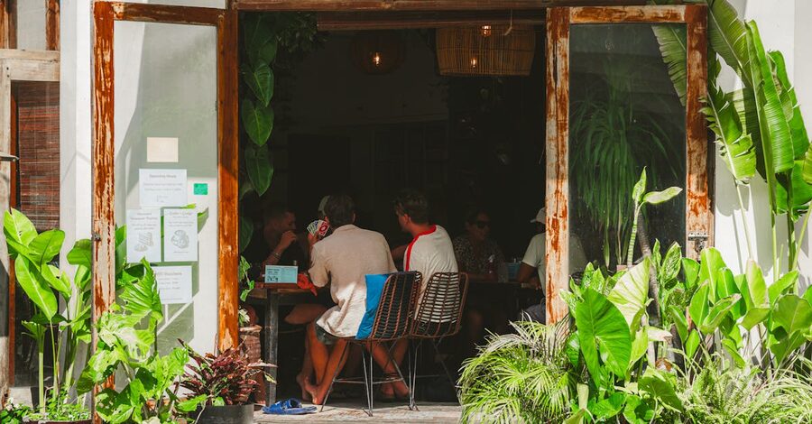 A relaxed group of guests at a tropical Ubud cafe surrounded by indoor plants