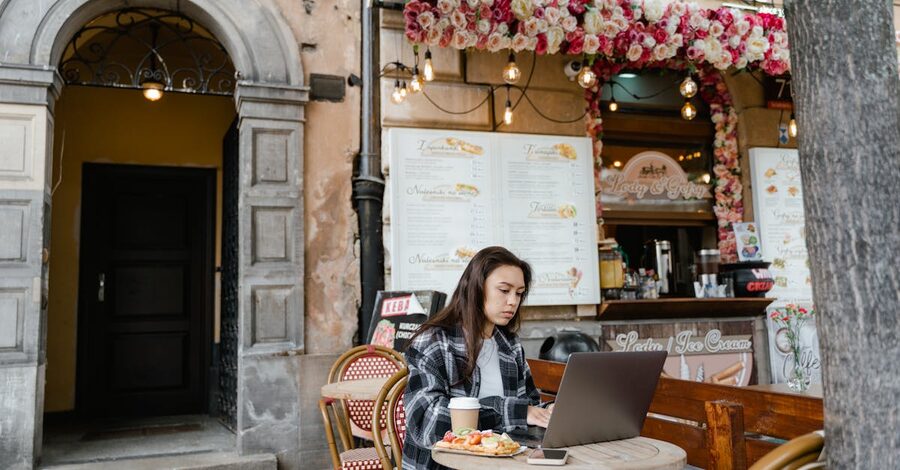 A digital nomad working from a laptop at an Ubud cafe with a coffee