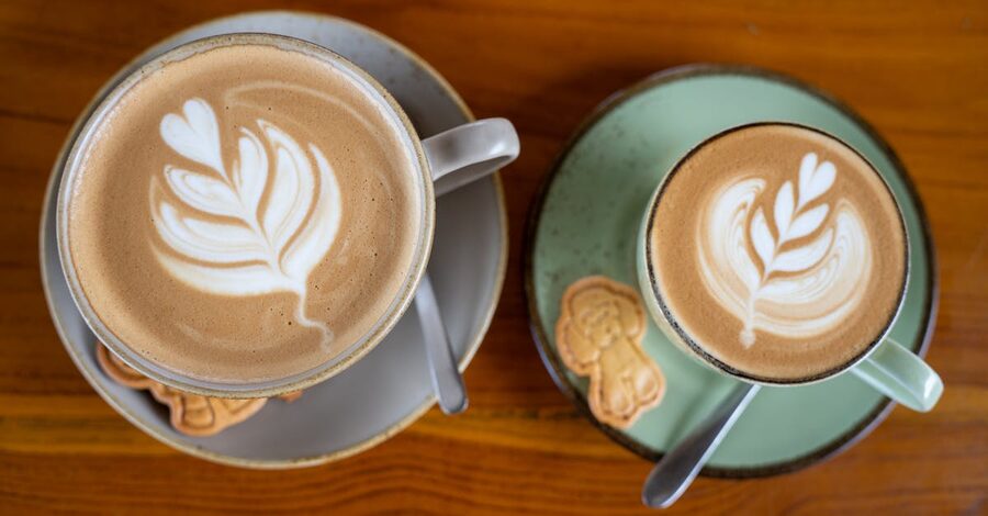 Two flat white coffees with cookies on a wooden table at an Ubud cafe