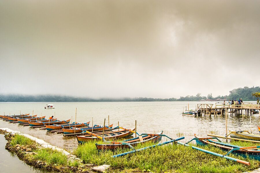Traditional jukung outrigger boats on Lake Bratan with mist over the water