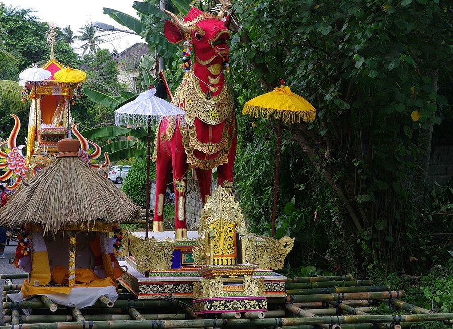 Decorated red lembu bull sarcophagus with ceremonial umbrellas before ngaben Bali