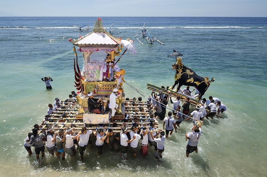 Ngaben procession at the sea Nusa Penida Bali with bade tower carried into shallow water