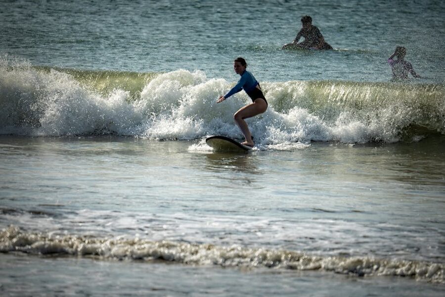 Beginner surfer riding a small Kuta-style wave on a long board