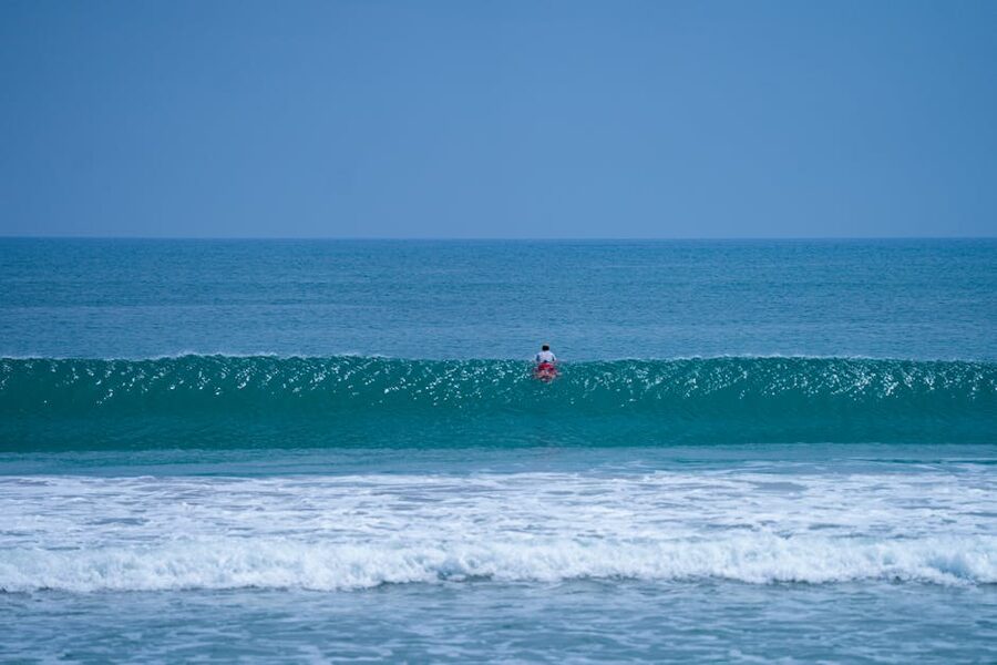 Lone surfer paddling out at Kuta Beach Bali on a clear day