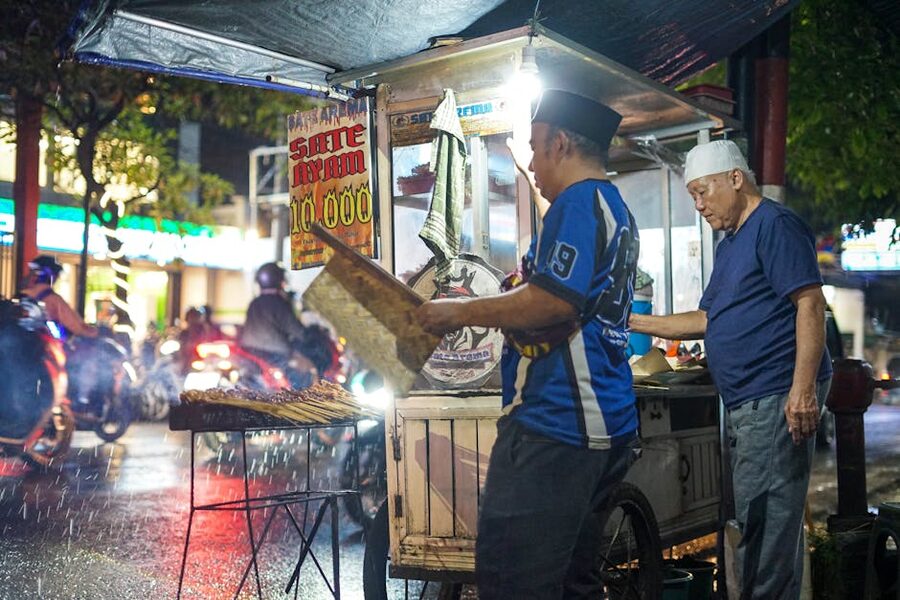 Indonesian sate ayam being grilled over coals at night