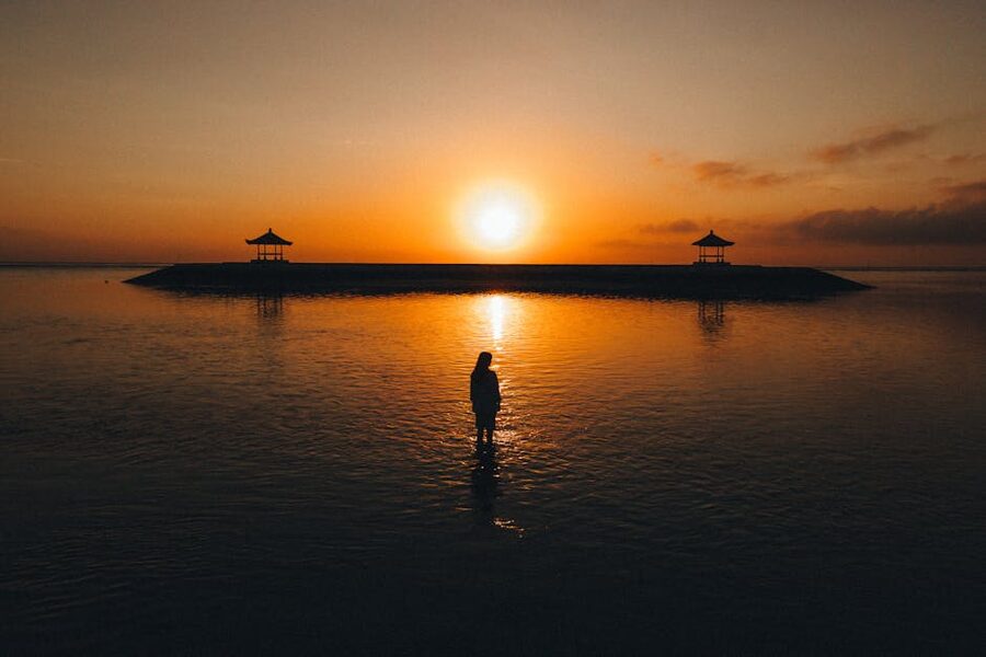 Silhouette at Sanur sunrise with traditional pavilions, Bali