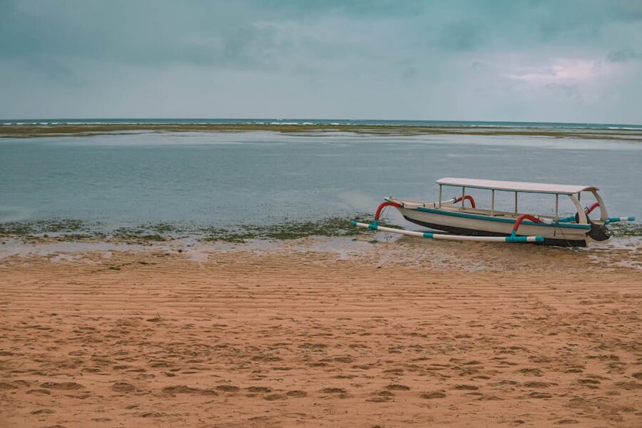 Traditional jukung outrigger boat resting on Sanur beach at low tide