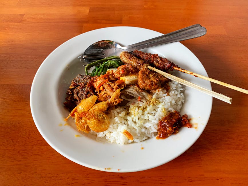 Plate of Balinese nasi campur with rice, satay, vegetables and sambal