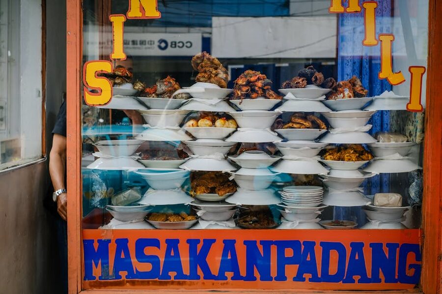 Window display of stacked Padang food plates at a Masakan Padang warung