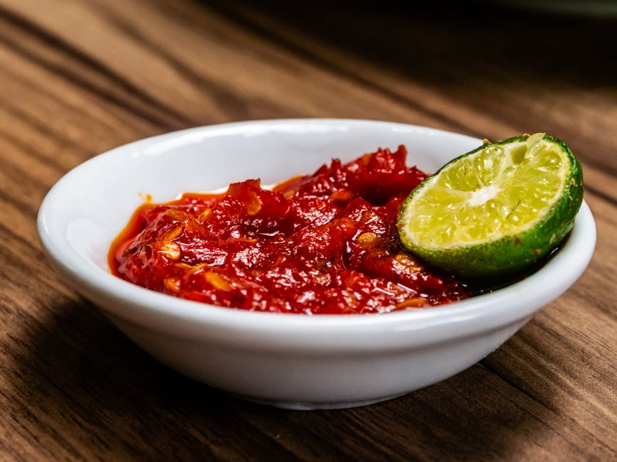 A small white bowl of spicy Indonesian sambal with a wedge of lime