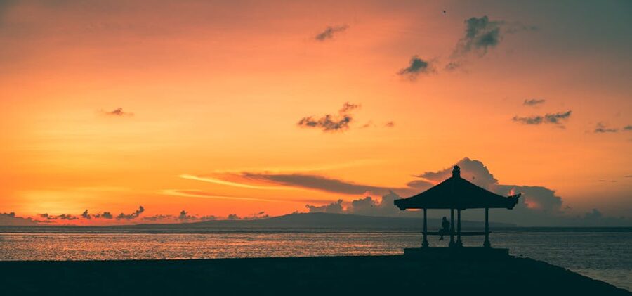 Sunset over Sanur Beach Bali with a beach hut silhouette on the sand