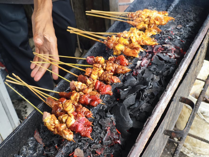 Indonesian sate skewers cooking over charcoal at a warung grill
