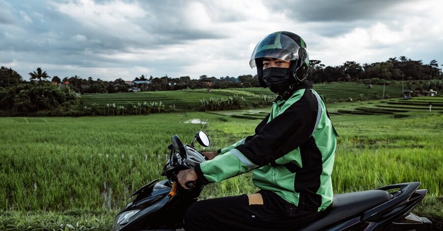 A rider on a scooter in front of green Bali rice fields