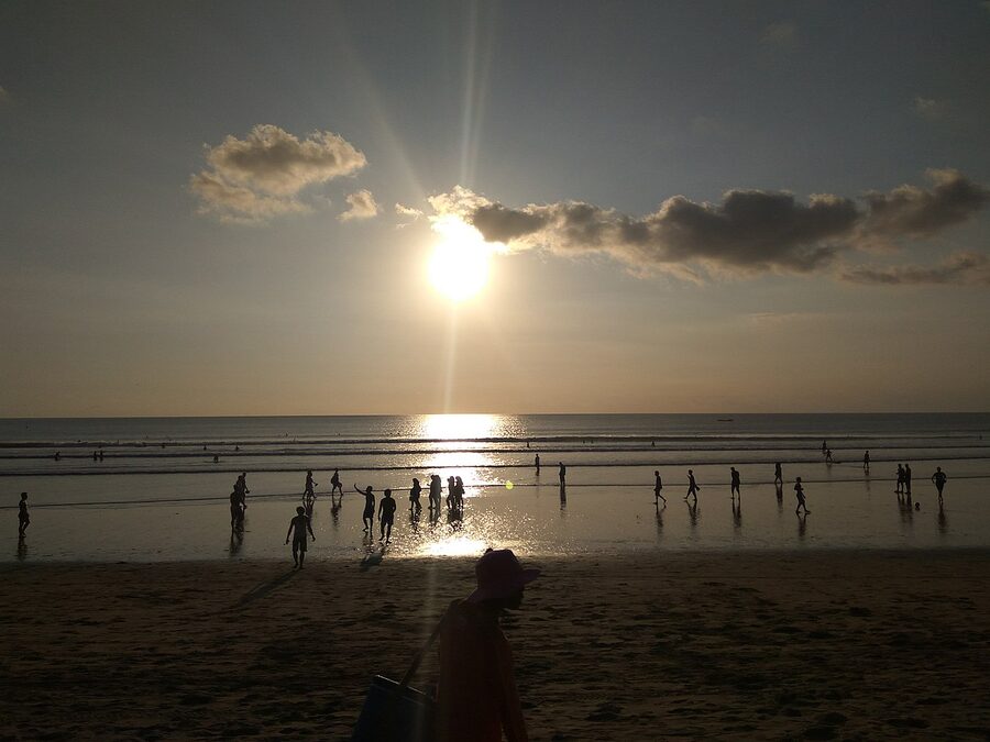Pantai Kuta Bali at sunset with crowd silhouettes against the orange sky