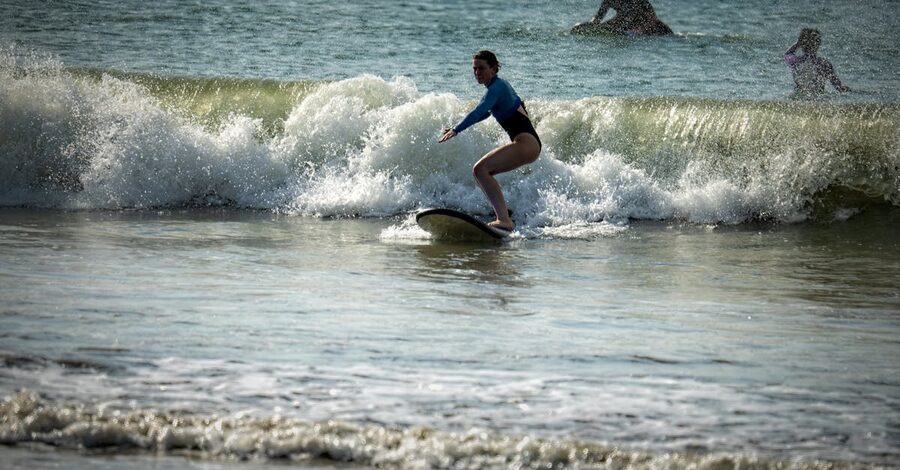 Surfer riding a small wave on a Bali beach, the kind of forgiving wave Canggu specialises in