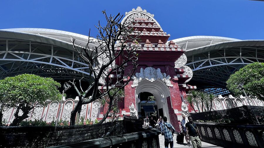 DPS Bali airport terminal exterior with traditional red Balinese gateway